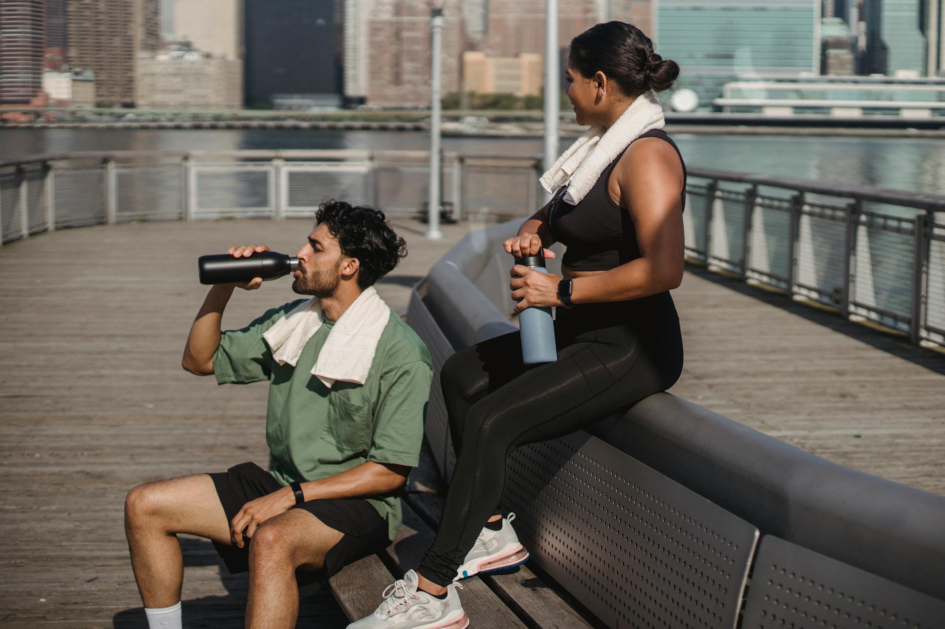man and woman drinking water after exercising