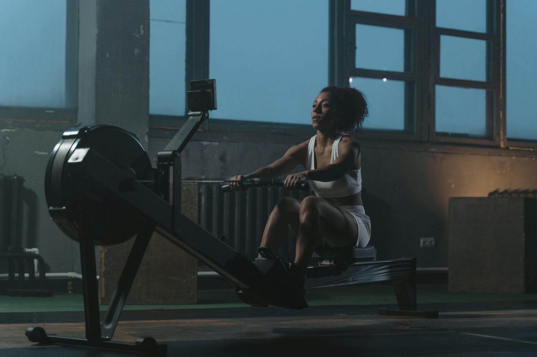 woman in white tank top sitting on black exercise equipment