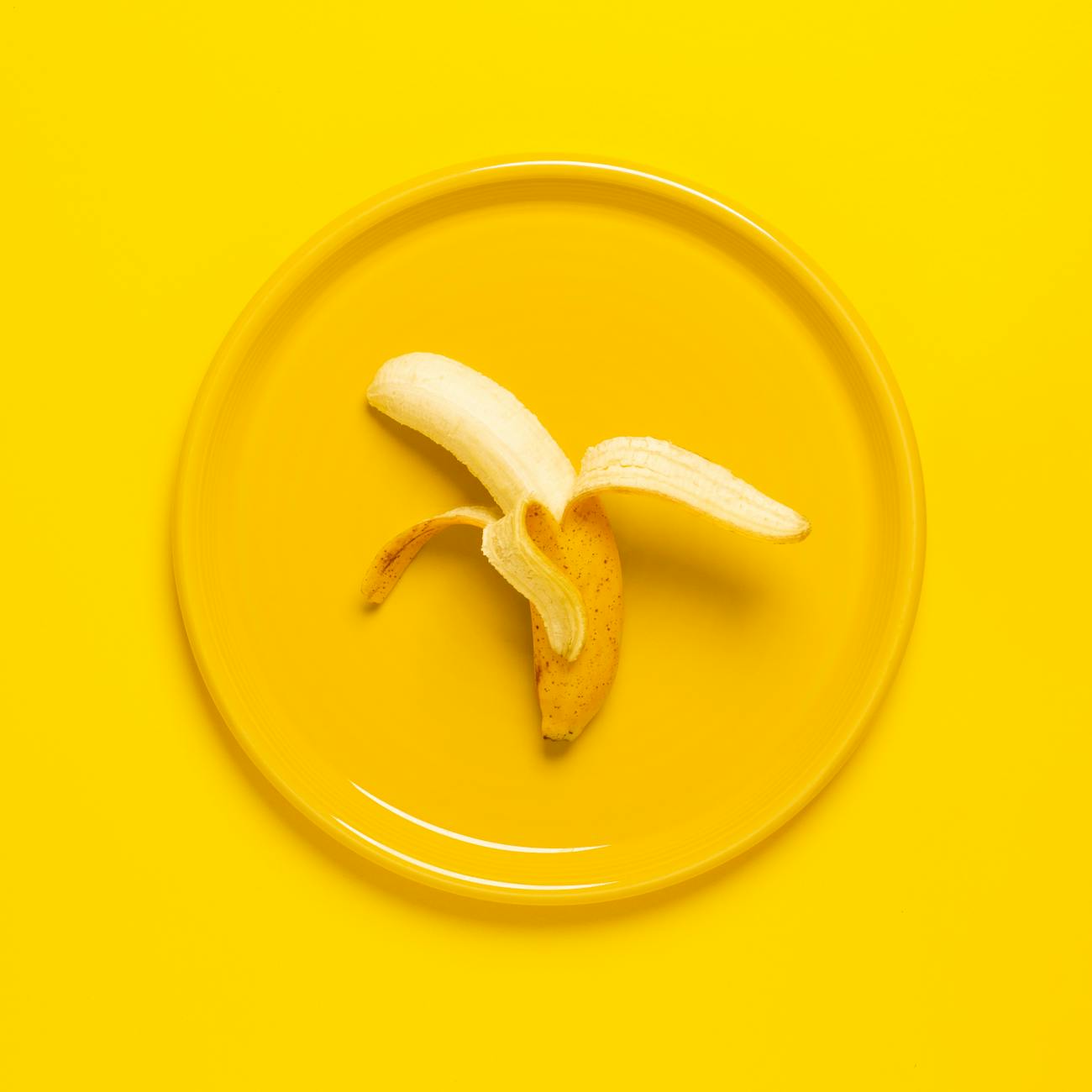 photo of peeled banana on yellow plate and background